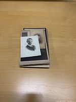 Stack of cabinet photos with the top photo showing a black and white portrait of a man in a suit.