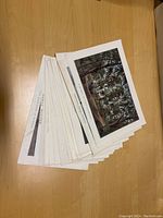 Stack of colorful lithograph prints from the set seen on wood table surface.