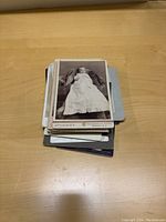 Stack of vintage black and white cabinet photos with the top photo showing a baby in a christening gown.