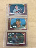 Three 1955 Bowman baseball cards displayed in protective sleeves; Bob Neiman at top, Charles King in middle, Paul Giel at bottom.