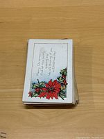 Stack of vintage Christmas postcards with a poinsettia and holly design and season's greeting on top.