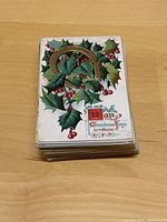 Stack of vintage Christmas postcards with holly and horseshoe design visible on top.