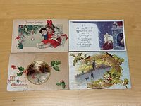 Four vintage Christmas postcards arranged on table showing holiday scenes such as children with toys and pets, Christmas greetings, holly, and winter illustrations.