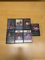 Seven Linda Ronstadt cassette tapes arranged on a wooden surface, showing front covers including artwork and album titles.