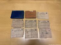 12 WWII era war ration books arranged on wood surface, showing different states of wear and some tears.
