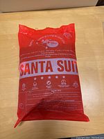 Red plastic package holding the unopened Santa suit with noticeable tear on the packaging side.