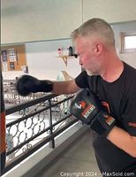 Instructor wearing black Phoenix Boxing gloves punching a heavy bag inside gym