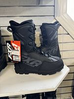 Pair of black FXR X-Cross Pro boots displayed on shelf