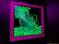 Square illuminated mirror with laser-engraved kraken and ship design glowing green, framed in a solid color frame.