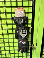 Pair of FXR Combat snowmobile gloves hanging on display grid