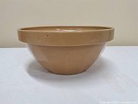 Side view showing the bowl's faceted exterior design and tan glaze finish.