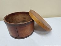 Exterior view of round wooden storage container with lid set to side