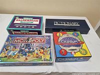 Four boxed board games: Absolute Balderdash, Pictionary, Monopoly Disney Edition, and Cranium.