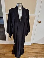 Full view of black Japanese kimono displayed on a mannequin, showing garment shape and drape.