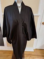 Front view of the black kimono displayed on a mannequin, showing its simple and elegant exterior.