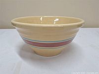Front view of the vintage mixing bowl showing beige color with blue and maroon stripes.