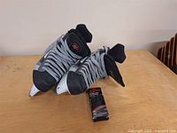 Pair of men's CCM hockey skates size 9 on wooden surface with gray laces, showing white blade holders and steel blades. Extra hockey laces included in packaging visible.