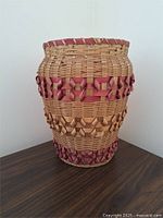 Full front view of a 12-inch tall Native Mohawk handwoven basket with natural and purple ash splints placed on a dark wood surface.
