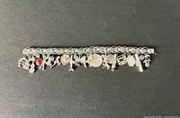 Photo showing full length of sterling silver charm bracelet with all 19 charms attached in a row on black background