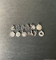 All 13 sterling silver charms laid out flat against a dark background showing individual designs including snowflake, hearts, holiday date, animals, and letters.