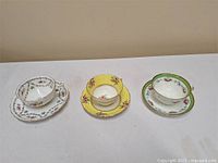Three vintage bone china teacup and saucer sets side by side showing different floral and colored designs.