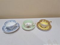 Three vintage bone china teacups with matching saucers, showing the cups upright