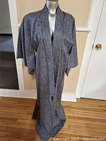 Full view of vintage Japanese kimono displayed on a mannequin against a white door background, showing the garment's length and sleeve detail.