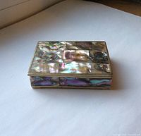 Front angled view of the closed rectangular sterling silver trinket box showing colorful mother of pearl inlay on lid and sides.