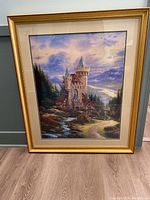 Full view of the framed Thomas Kinkade Guardian Castle print showing the castle in a landscape with a path and mountains in the background.