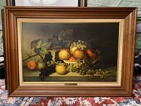 Framed still life picture-print showing an arrangement of fruits including grapes, pears, and peaches on a plate with vine leaves.