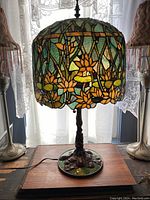 Full lamp front view showing stained glass shade with water lilies and brass base on tabletop.
