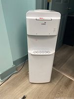 Front view of the white Oasis water cooler showing control panel, water spouts, and drip tray.