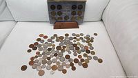 Photo of loose miscellaneous world coins and tokens scattered on white background, featuring a variety of sizes and metals.