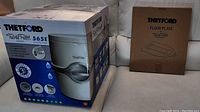 Full boxed view of Thetford Porta Potti 565E and separate boxed floor plate mounting bracket.