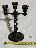 Front view of antique triple candle holder with barley twist wooden stem and copper candle cups with measuring tape showing approximate width.