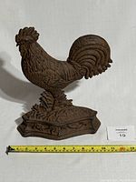Side view of the rooster door stop showing detailed feather patterns, base ornamentation, and length approx 11.5 inches.