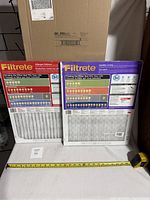 Two Filtrete furnace filters displayed side by side, one Allergen Defense with red packaging and one Healthy Living with purple packaging, size 16x20x1.