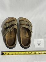 Top view of used beige Birkenstock slide sandals showing straps and footbed.