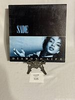 Front cover of Sade's Diamond Life vinyl record album, showing the title and cover photo.