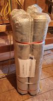 Four rolls of flooring underlay wrapped in protective silver packaging, stacked and secured with bands.