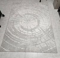 Top view of the carpet showing the concentric ring design in white and grey color placed on a light tiled floor.
