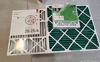 Photo showing one Honeywell 20x25x4 air filter with a white frame and grid backing plus one 3-pack of HDX 12x12x1 filters with green filter media in a white frame, packaging labeled FPR 5, dust and pollen