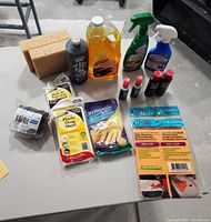 Photo of all items in the lot arranged on a table including bottles, sponges, gloves, cloths, and cleaning compounds