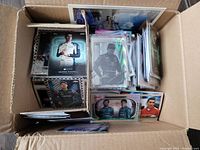 Card collection displayed inside a divided cardboard box showing multiple Formula 1 driver cards in protective sleeves, visible drivers George Russell and others