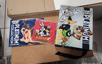 Photo showing the gift box closed with Looney Tunes Platinum Collection Volume One artwork and two metal signs featuring characters like Bugs Bunny and Tasmanian Devil.