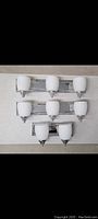 Three chrome bathroom light fixtures arranged on a surface, two 3-light fixtures and one 2-light fixture, viewed from the front.