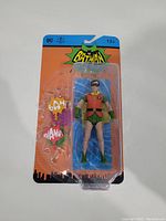 Front view of McFarlane Batman Classic TV Series Robin figure in original packaging with two BANG/WHAM style sound effect accessories.