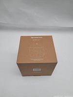 Original packaging box for the Nespresso Mia Display capsule dispenser, brown with product illustration and Nespresso branding.