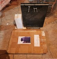 Photo showing black and white rotating display stands with peg holes and original packaging on floor.