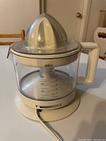 Braun electric juicer assembled showing juice container, juicer cone, and power cord on base